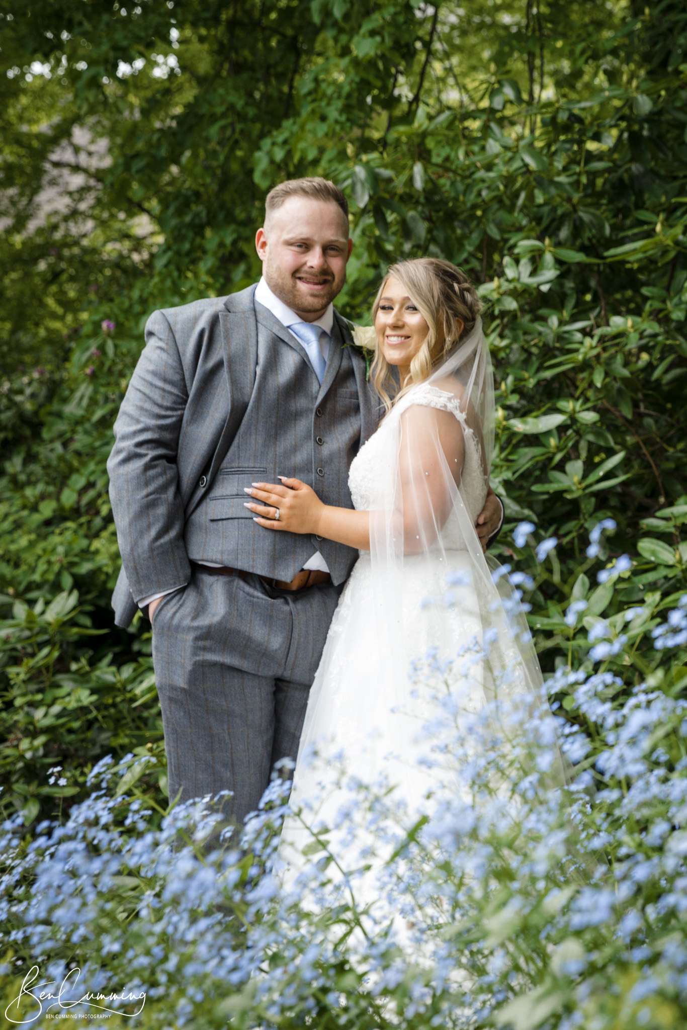 Bride and Groom Pose in forget me nots at Manor House Lindley