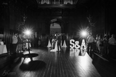 A black and white photo of a bride and groom standing in a dark room.