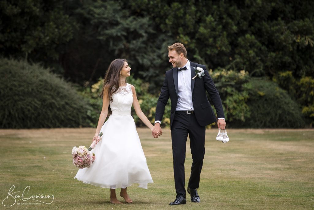 A Carlton Towers Wedding Photographer captures a bride and groom holding hands in the grass.