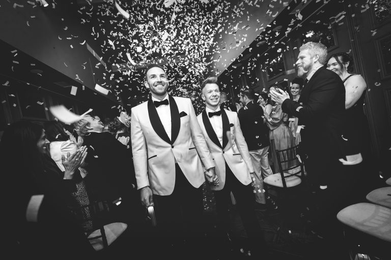 Grooms walk down the aisle with confetti on their wedding day