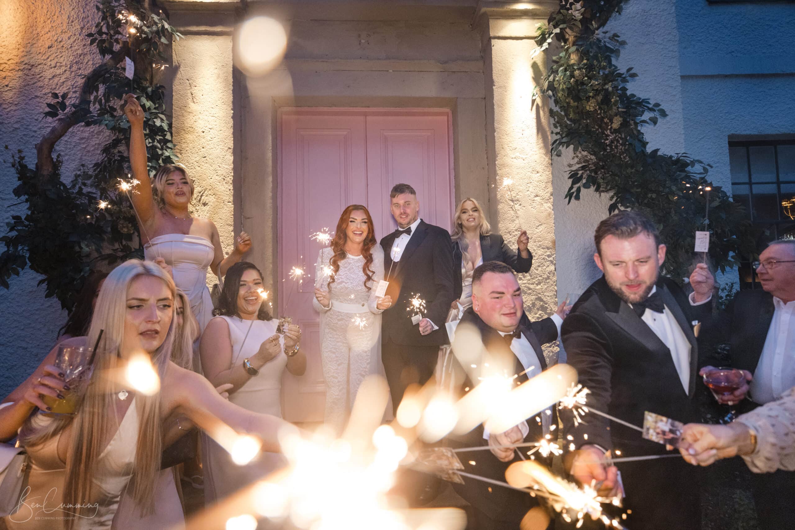 Newlyweds walking through a sparkler guard of honour outside The Croft Hotel