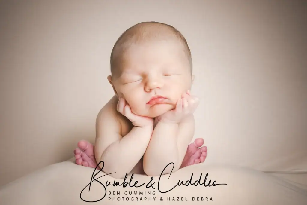 a newborn baby rests peacefully with their chin in their hands and eyes closed, posed on a soft, light surface. the image features the logo "bumble & cuddles photography & hazel debra" at the bottom. ben cumming photography wedding photographer yorkshire